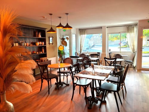 Élégante salle à manger de l'hôtel Maisons Delphine Le Cottage à Villers-sur-Mer avec chaises noires, accents orangés et vue sur mer