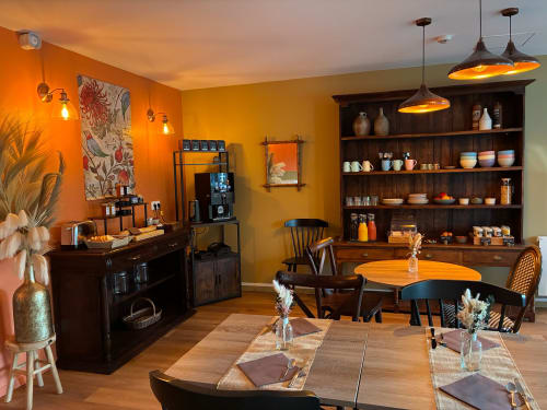 Espace chaleureux de couleur orange pour la salle à manger et lounge aux Maisons Delphine Le Cottage à Villers-sur-Mer, avec tables en bois, luminaires suspendus