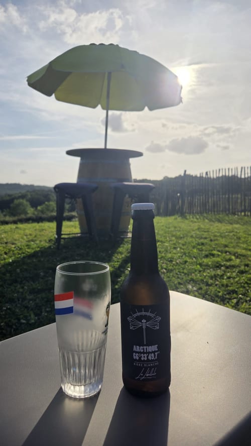 Verre de bière avec parasol offrant vue sur les vignobles du Home Sweet Lodge Glamping Aquitaine