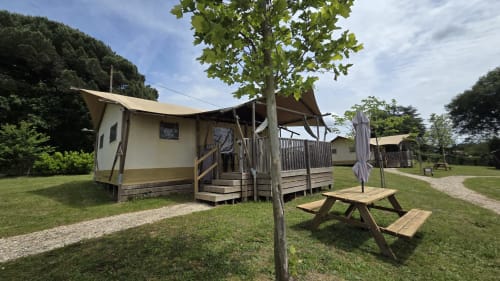Glamping cottage Home Sweet Lodge avec terrasse en bois, table de pique-nique et auvent ombragé en Aquitaine rurale