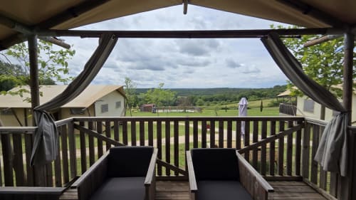 Terrasse ombragée avec transats panoramique sur la campagne verdoyante du glamping Home Sweet Lodge Aquitaine