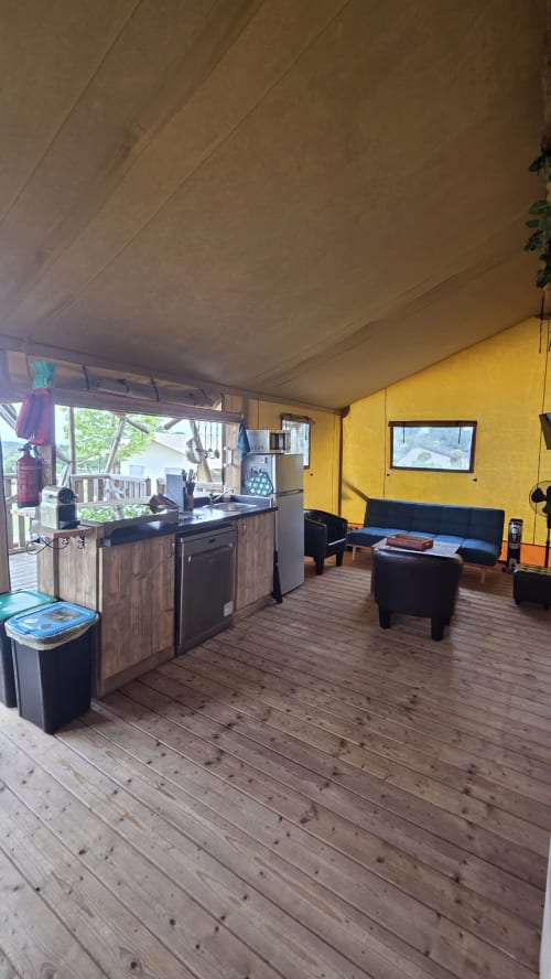 Intérieur lumineux de cottage glamping jaune vif à Home Sweet Lodge avec cuisine aménagée, salon, parquet et vue montagne