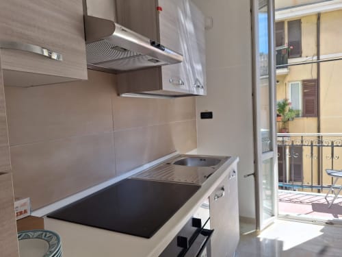 Cucina moderna con elettrodomestici in acciaio inox e balcone con vista sulla città presso Kate Apartments, Genova