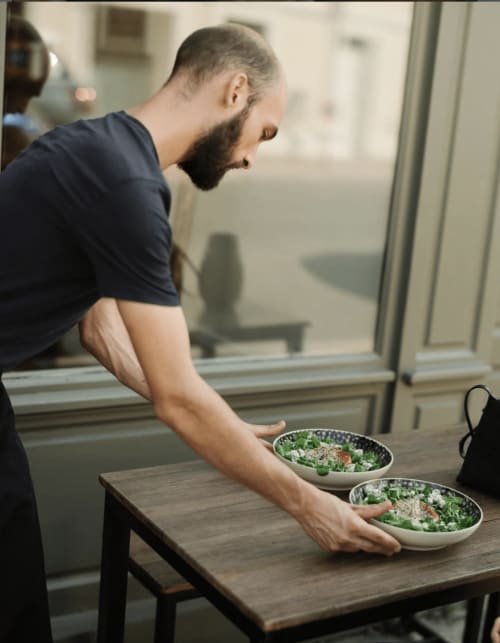 Homme barbu servant des salades vertes fraîches aux Maisons de Pierre et Valérie, une maison d'hôtes à Honfleur
