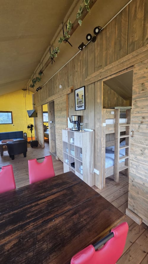Intérieur de chalet en bois moderne avec chaises roses, table de salle à manger foncée, coin séjour et rangements à Home Sweet Lodge
