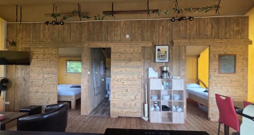 Intérieur du glamping "Home Sweet Lodge" avec murs en bois, chambre, salon, kitchenette et murs jaunes