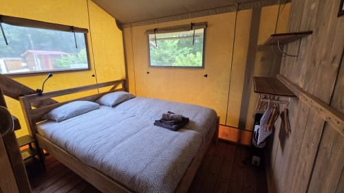 Gezellige glampingkamer in Home Sweet Lodge met queensize bed, gele muren, houten details en uitzicht op Aquitanië