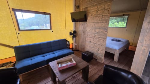 Interieurbinnenruimte van glamping lodge met blauwe bank, bed, televisie en houten meubels in Home Sweet Lodge Aquitaine