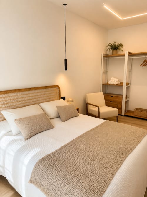 Dormitorio moderno en Alojamientos Apoio 360 en Caldas de Reis con cabecero de ratán, ropa de cama crema, lámpara colgante y madera