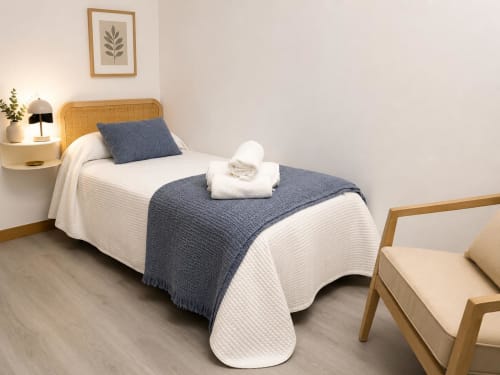 Dormitorio moderno en Alojamientos Apoio 360 de Caldas de Reis con cama de marco de madera, ropa de cama azul y blanca, y muebles de madera