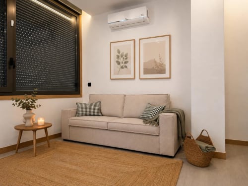 Acogedora sala de estar en Alojamientos Apoio 360 con sofá beige, muebles de madera y arte botánico en las paredes