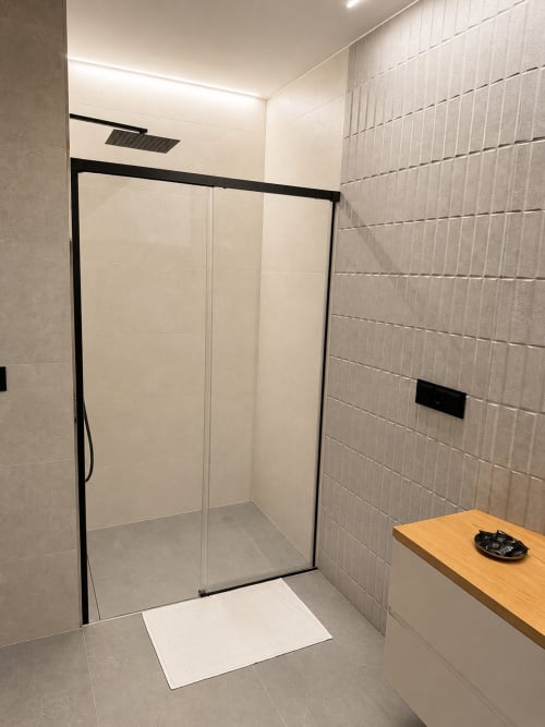 Baño moderno con ducha a ras de suelo, mampara de cristal con marco negro y tocador de madera en Alojamientos Apoio 360, Caldas de Reis