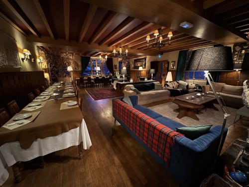 L'élégant espace de restauration et détente de la Domerie à Aubrac avec poutres en bois, cheminée et mobilier tartan écossais
