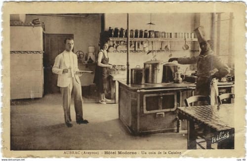 Cuisine historique de l'Hôtel Moderne à Aubrac, Aveyron, présentant les équipements culinaires du début du XXe siècle et le personnel préparant les repas