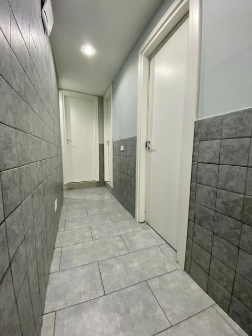 Modern hallway with gray tile walls and white doors in Neapolis Tecnotourist apartment, Italy