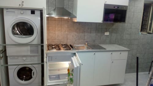 Kitchen and laundry area with gas stove, sink, refrigerator, and stacked washer-dryer in apartment at Neapolis Tecnotourist