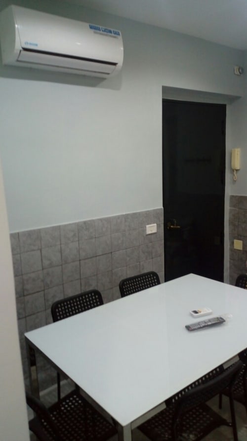 Modern dining area in Neapolis apartment with white table, black chairs, air conditioning unit, and gray tile accents