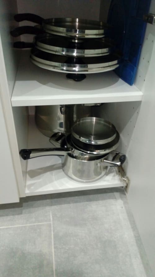 Kitchen cabinet with stacked cookware and stainless steel pots in Neapolis Tecnotourist apartment