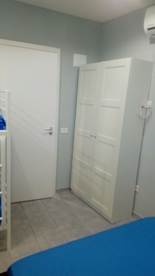 Modern bedroom with white doors and light blue walls at Neapolis Tecnotourist apartment in Italy