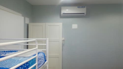 Modern bedroom in Italian apartment with twin bed, white wardrobe, air conditioning, and light blue walls at Neapolis