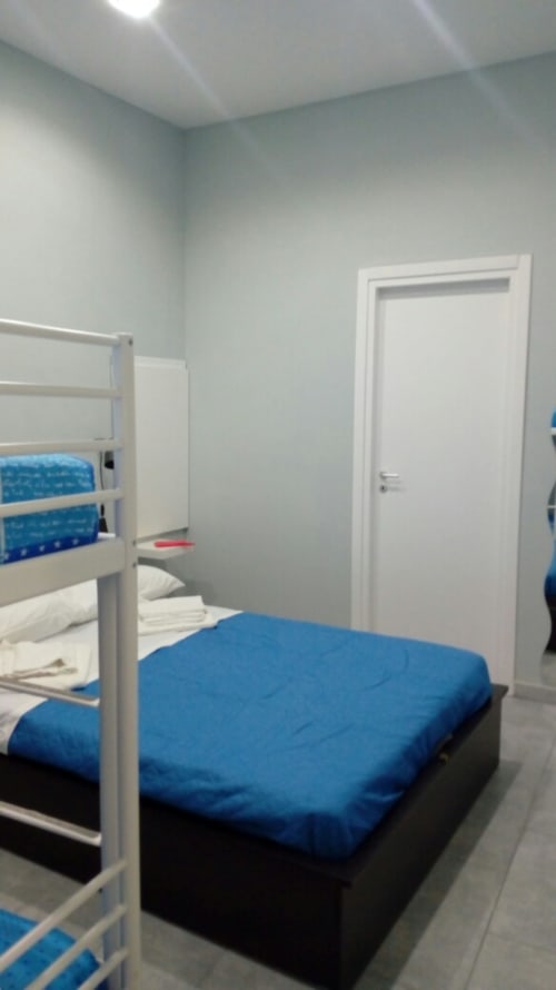 Modern bedroom at Neapolis Tecnotourist with blue bedding, white bunk beds, and minimalist décor in Naples, Italy