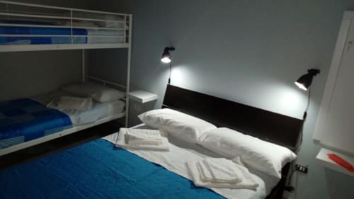 Modern bedroom with double bed, bunk bed, and overhead reading lights at Neapolis Tecnotourist apartment in Italy