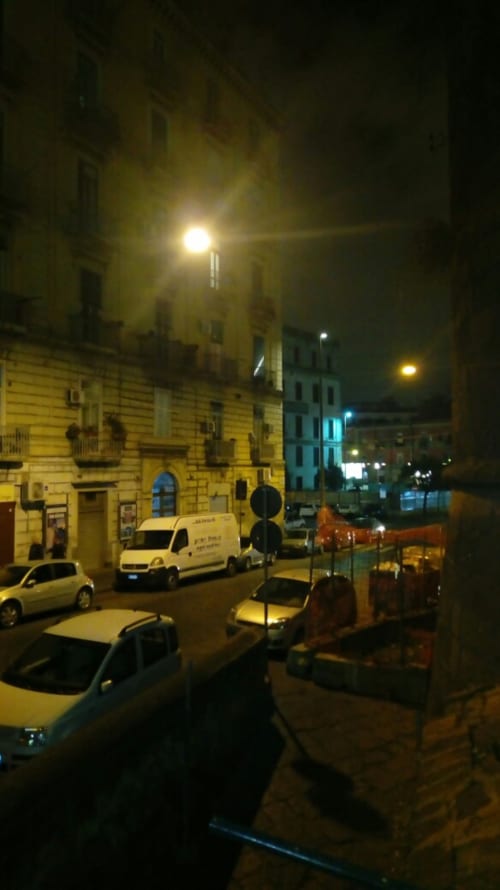 Night street view of Neapolis Tecnotourist BnB in Naples, Italy showing parked cars and historic buildings