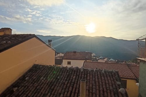 Tetti in terracotta e montagne all'alba, appartamento Torre del Borgo a Valle Mosso