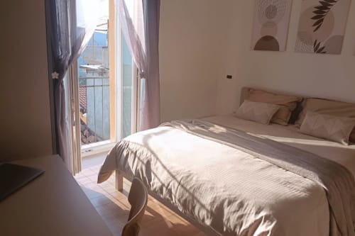 Camera soleggiata nell'appartamento Torre del Borgo, Valle Mosso, con letto, porte della balconata aperte e vista sulle montagne