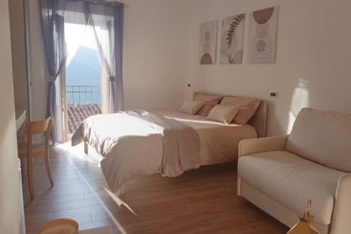 Camera luminosa nell'appartamento Torre del Borgo con balcone vista mare, biancheria neutra e arte moderna presso The Gentle Home