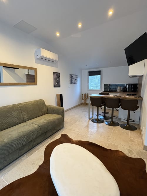 Studio moderne au Mas Aurel de Provence avec séjour ouvert, kitchenette, canapé et bar à Peypin