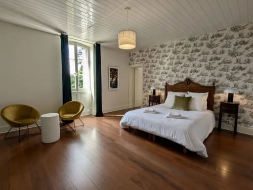 Chambre élégante du Domaine du Faure avec parquet, papier peint à motifs et mobilier vintage