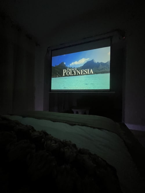 Écran de projection affichant un documentaire de voyage sur la Polynésie française dans une salle sombre de l'hôtel Le Mas Aurel de Provence