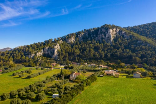 Vue panoramique de la vallée provençale avec champs verdoyants, falaises calcaires et village charme près de Peypin