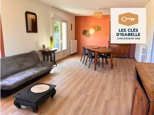 Spacieux séjour aux Clés d'Isabelle à Compreignac avec canapé, table à manger et mur d'accent orange