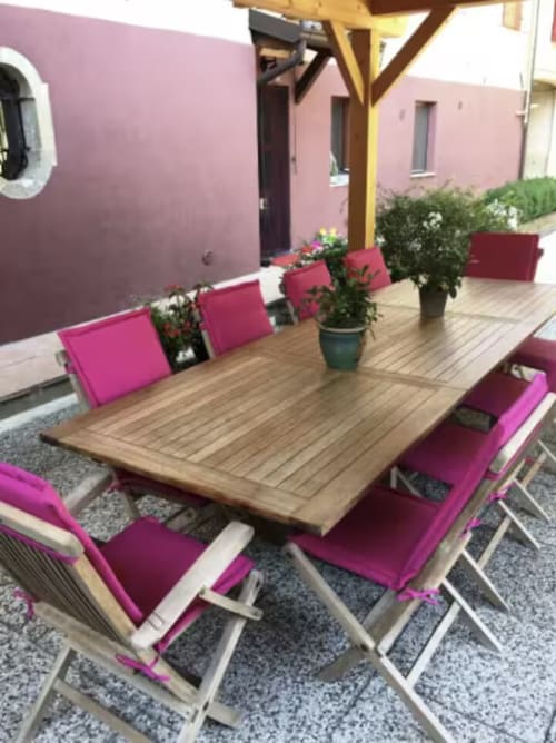 Patio esterno di Casa Mia Vacanza con tavolo in legno, sedie imbottite rosa, piante in vaso e pergolato in Italia