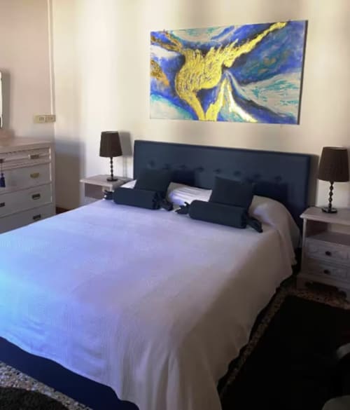 Elegante camera da letto a Casa Mia Vacanza B&B Italia con letto rivestito blu navy, biancheria bianca, opere d'arte moderna e lampade da comodino