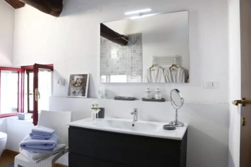Bagno moderno di Casa Mia Vacanza con vanità nera, piano bianco, specchio grande e eleganti rubinetterie