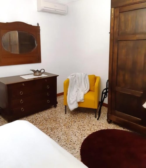 Camera Tripla Bordeaux a Casa Mia Vacanza con mobili in legno, sedia gialla e pavimento in terrazzo