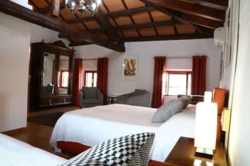 Lussuosa camera tripla presso Casa Mia Vacanza con travi in legno, biancheria bianca, tende rosse e design classico italiano