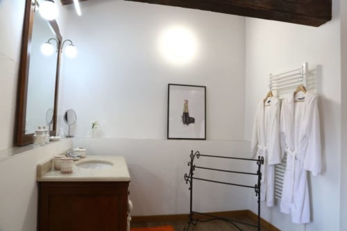 Elegante bagno di Casa Mia Vacanza con lavabo in marmo, specchio, scaldariscaldabagni e accappatoi bianchi
