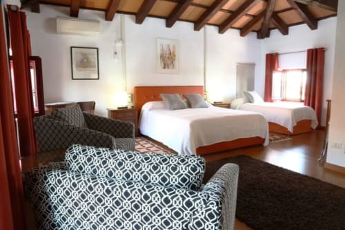 Ampia camera tripla di lusso a Casa Mia Vacanza con testiere arancioni, letti gemelli, poltrone decorate e travi in legno
