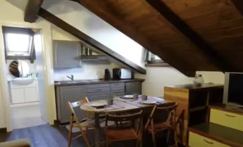 Mansarda con tavolo da pranzo, angolo cottura e travi in legno a Casa Mia Vacanza