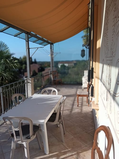 Terrazza di Mia Experience Monza con tavolo da pranzo, sedie, ombrellone arancione e vista sulla campagna