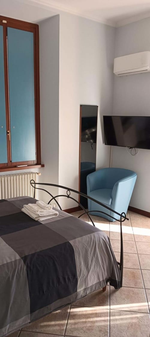 Stanza Stella di lusso a Mia Experience Monza con letto, poltrona blu, TV a parete e porta con specchio
