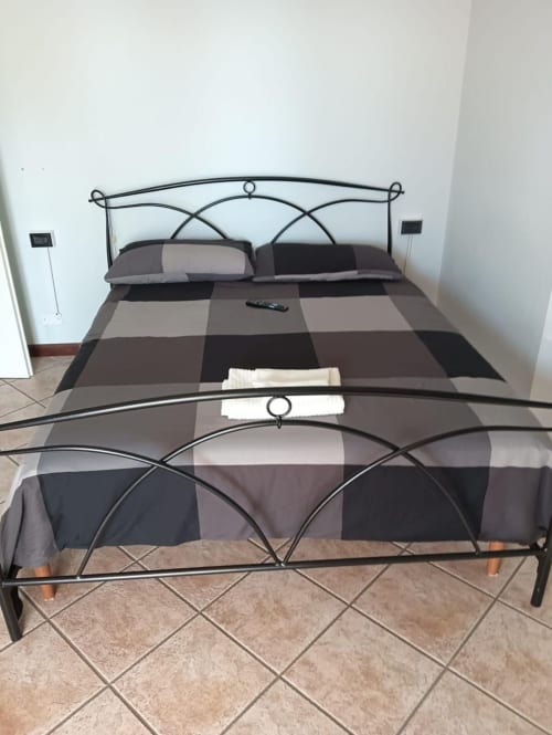 Letto in ferro battuto elegante con biancheria a quadri marroni nella Stella Luxury Room di Mia Experience B&B, Monza