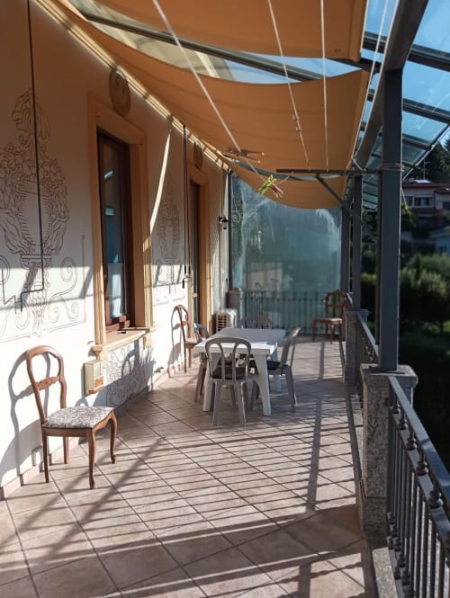 Terrazza soleggiata della camera lusso Mia Experience a Monza con tenda arancione, tavolo da pranzo e vista sulle montagne