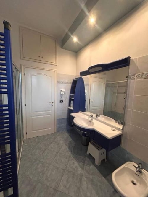 Bagno moderno nella Stella Luxury Room di Mia Experience Monza con doppio lavabo, doccia e portasciugamani blu