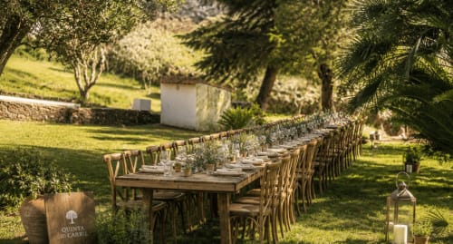 Mesa de madeira comprida decorada para hóspedes no frondoso jardim da Quinta Do Carril, hospedaria portuguesa