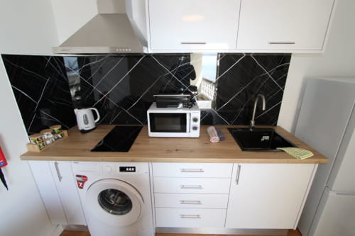Cocina moderna con mobiliario blanco, encimera de madera, backsplash de mármol negro y electrodomésticos integrados en villa de Funchal
